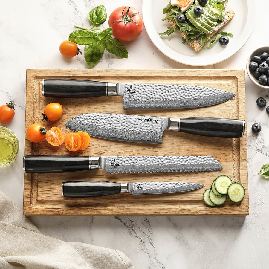 Shōjin Taru kockkniv, santokukniv, brödkniv och universalkniv på en skärbräda i ek med tomater och gurka
