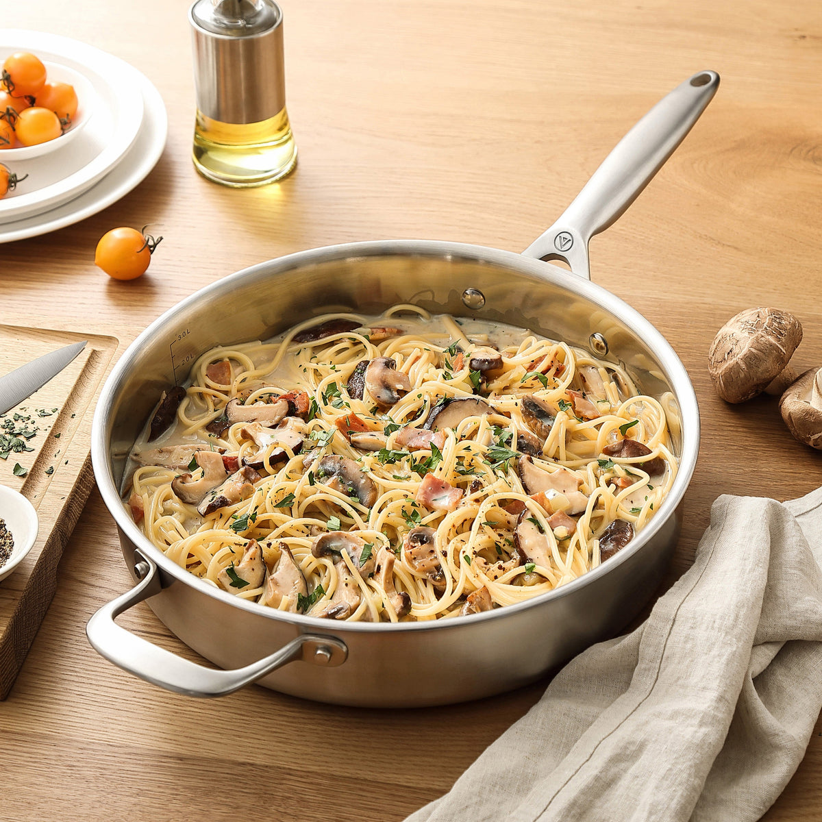 Pasta med svamp i en sautépanna i 3-Ply rostfritt stål på ett träbord