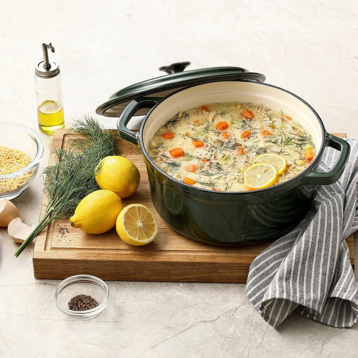 Mossgrön gjutjärnsgryta med kycklingsoppa, citron och dill på en skärbräda, locket lutat mot grytan