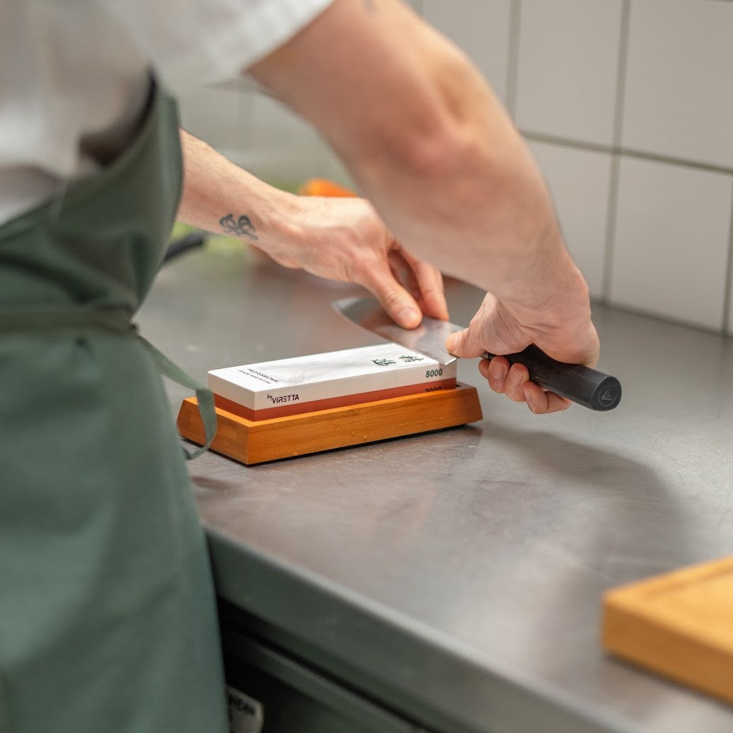 Bambuhållaren med Shōjin slipsten 3000/8000 medan en kniv slipas i ett restaurangkök