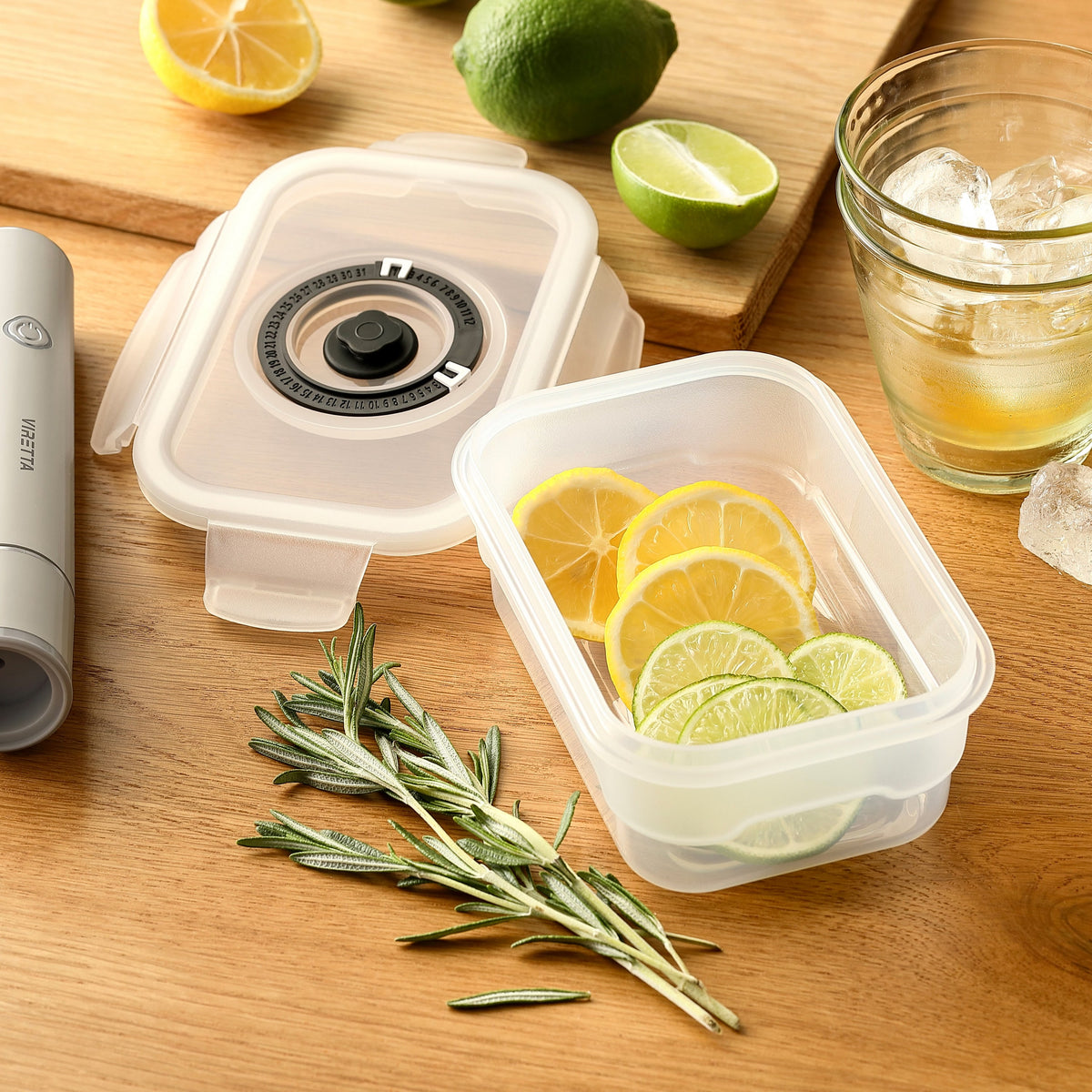 Vakuumbehållare i plast med citron- och limeskivor – locket och den elektriska vakuumpumpen ligger bredvid