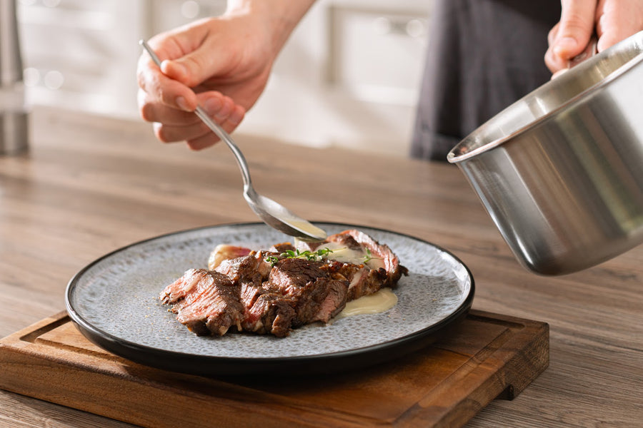 Sås hälls ur en kastrull över skivad biff