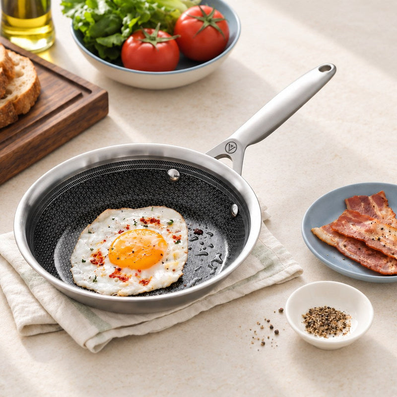 Stekt ägg i en stekpanna i 3-Ply Hybrid med bacon och bröd på ljus sten