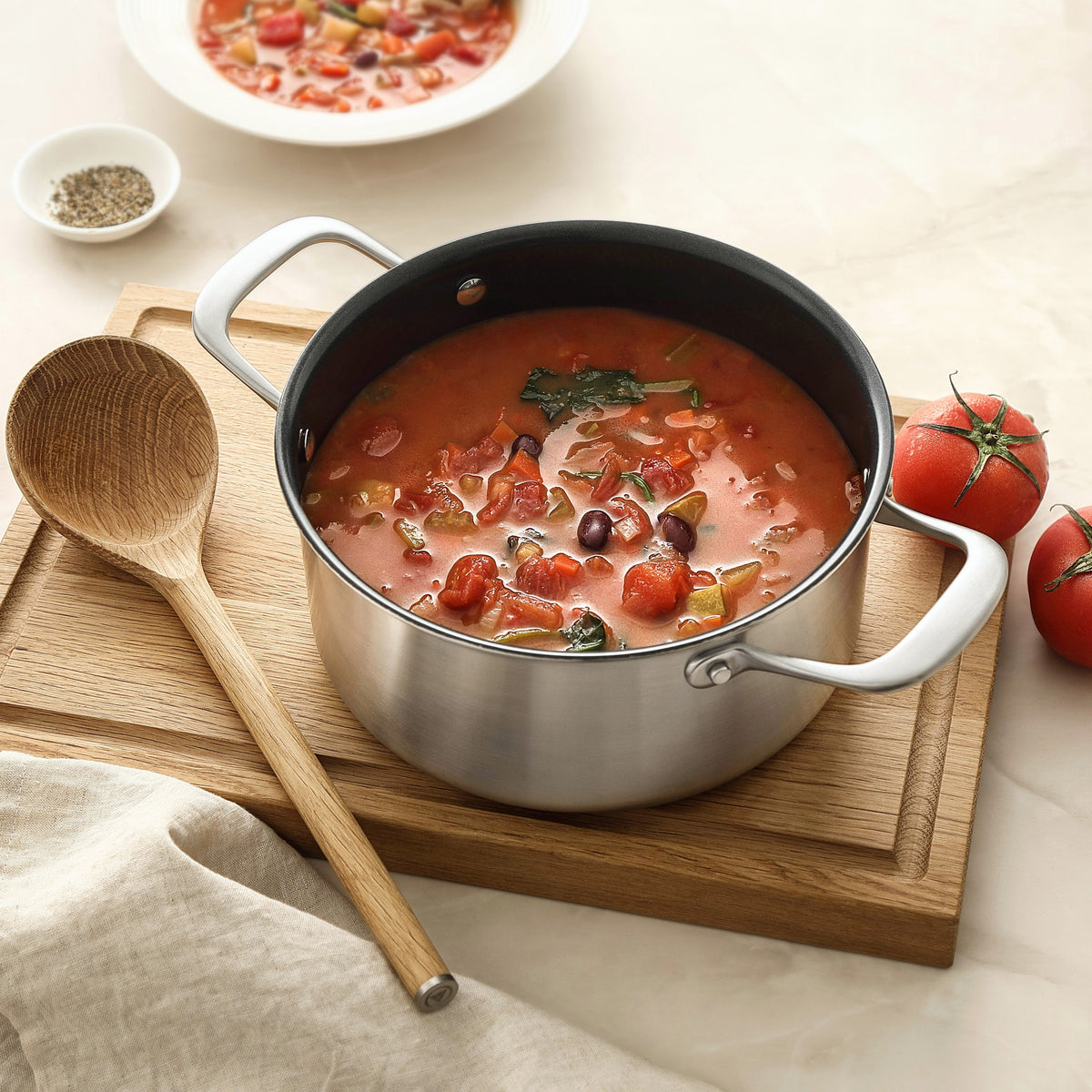 Tomatsoppa med grönsaker i en gryta i 3-Ply keramisk med en träsked