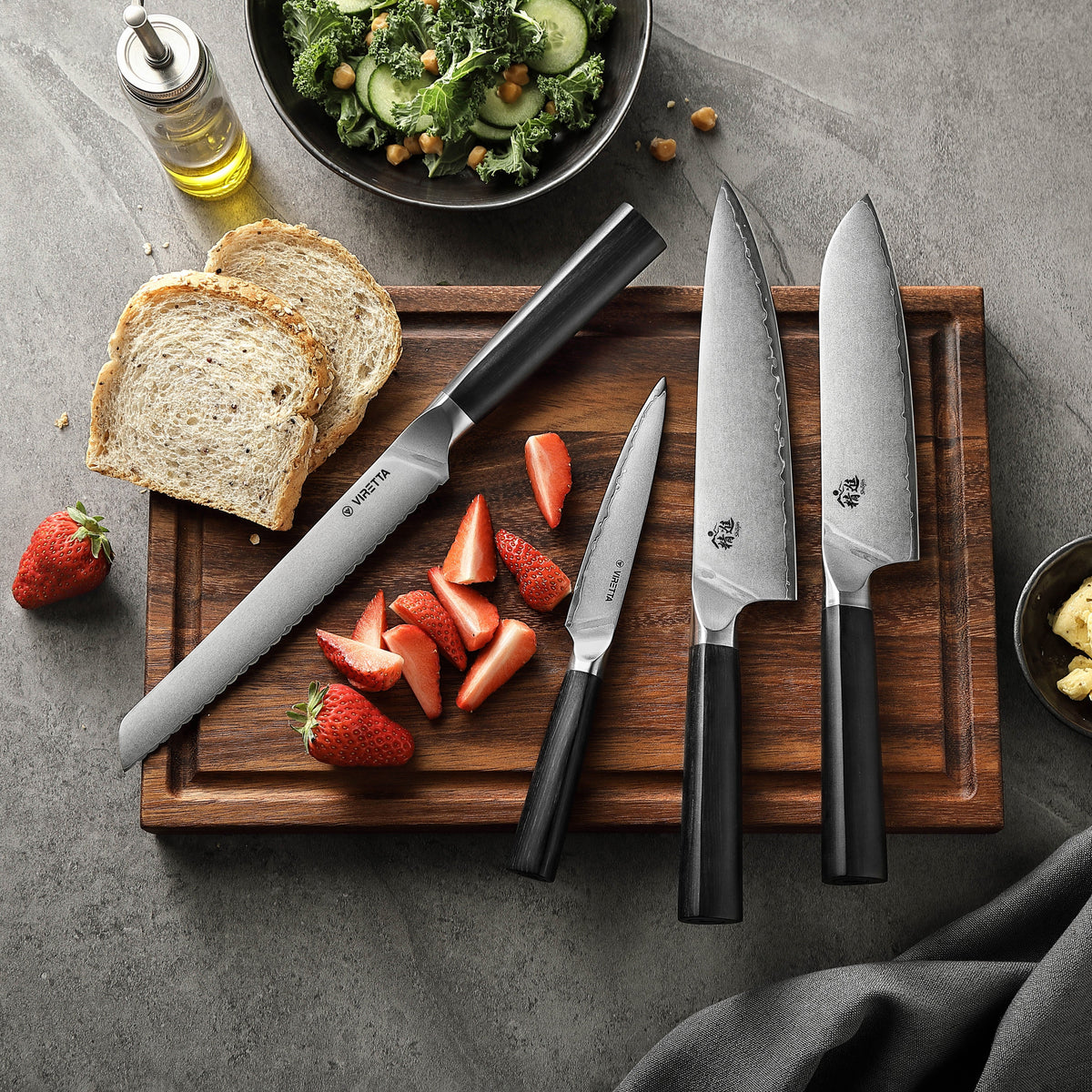 Shōjin Aira brödkniv, universalkniv, kockkniv och santokukniv på en skärbräda i valnöt med bröd och jordgubbar