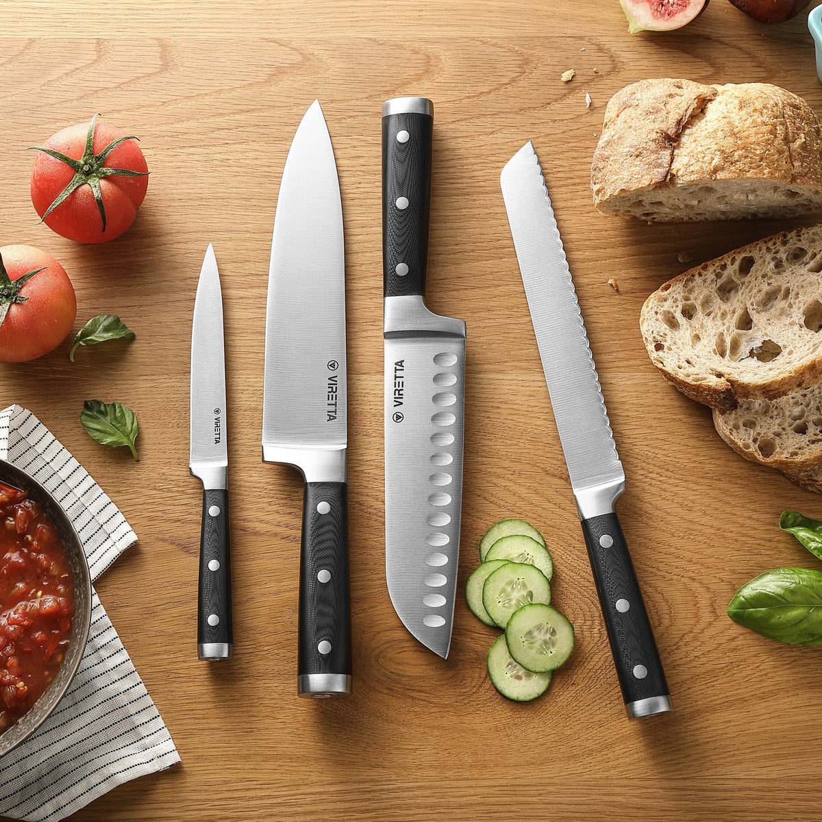 Classic brödkniv, santokukniv, kockkniv och universalkniv på ett träbord med bröd och tomater