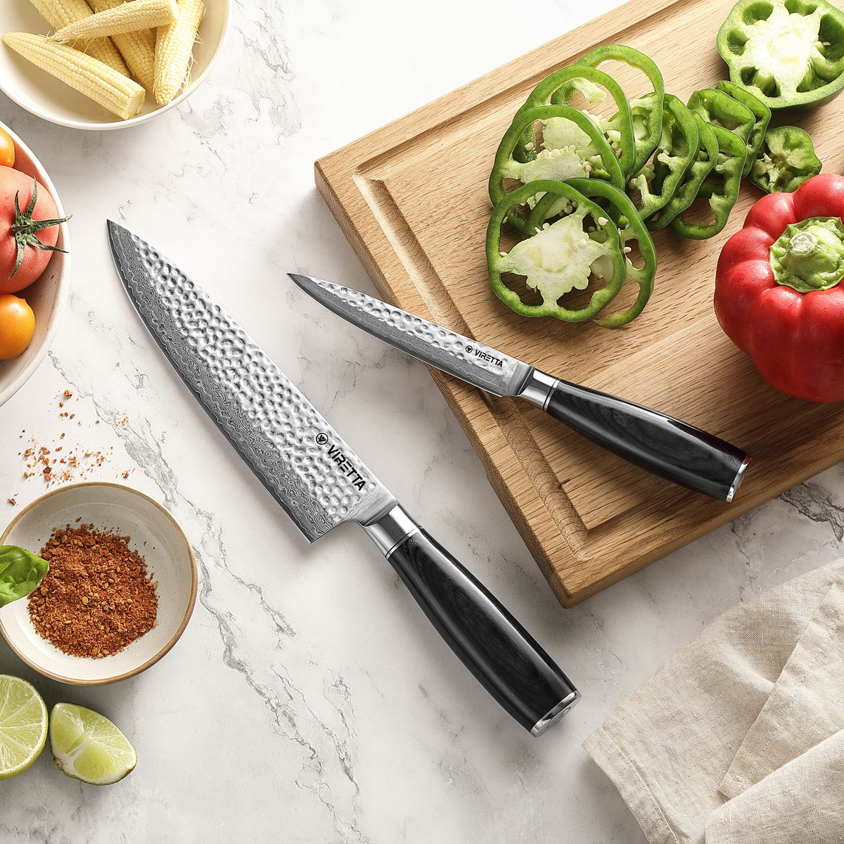 Shōjin Taru universalkniv och kockkniv på marmor och en skärbräda i ek med paprika