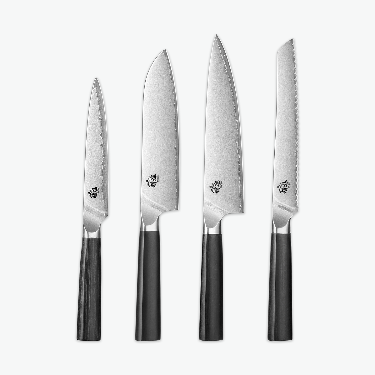 Shōjin Aira knivset – Signature: universalkniv, santokukniv, kockkniv och brödkniv mot ljus bakgrund