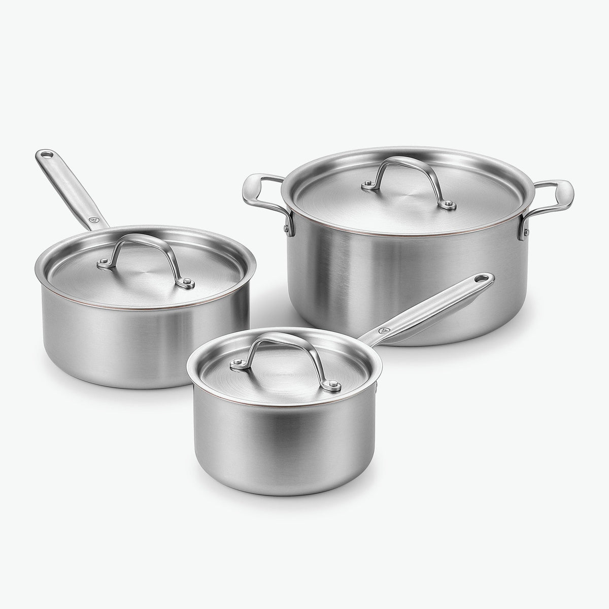 Gryta Trio i 5-Ply rostfritt stål med kopparkärna: kastruller Ø16 och Ø20 cm och gryta Ø24 cm, med lock i rostfritt stål, sett snett framifrån