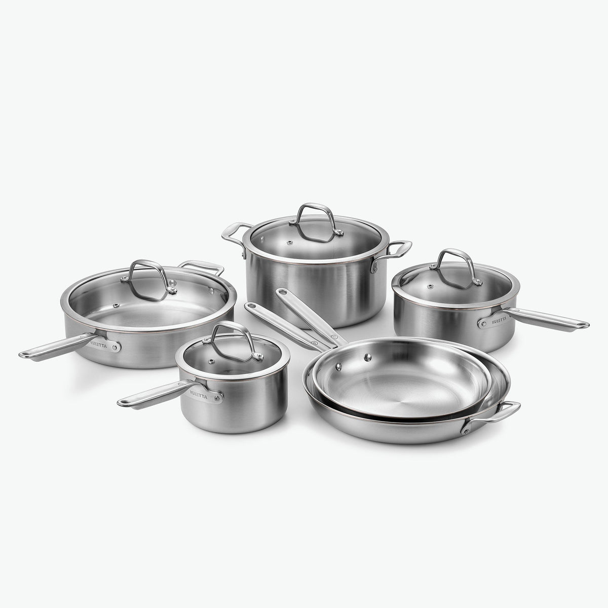 Kockset i 5-Ply rostfritt stål med kopparkärna: kastruller Ø16 och Ø20 cm, gryta Ø24 cm, sautépanna Ø28 cm och stekpannor Ø26 och Ø30 cm, med glaslock, sett snett framifrån