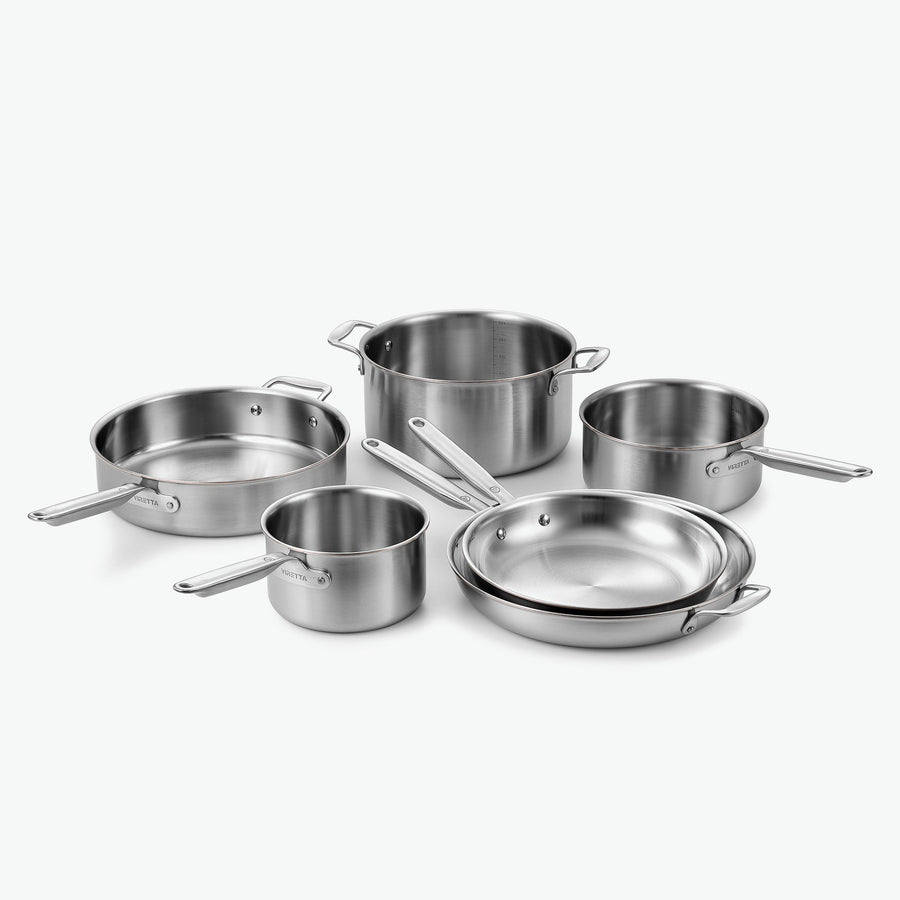 Kockset i 5-Ply rostfritt stål med kopparkärna: kastruller Ø16 och Ø20 cm, gryta Ø24 cm, sautépanna Ø28 cm och stekpannor Ø26 och Ø30 cm, utan lock, sett snett framifrån