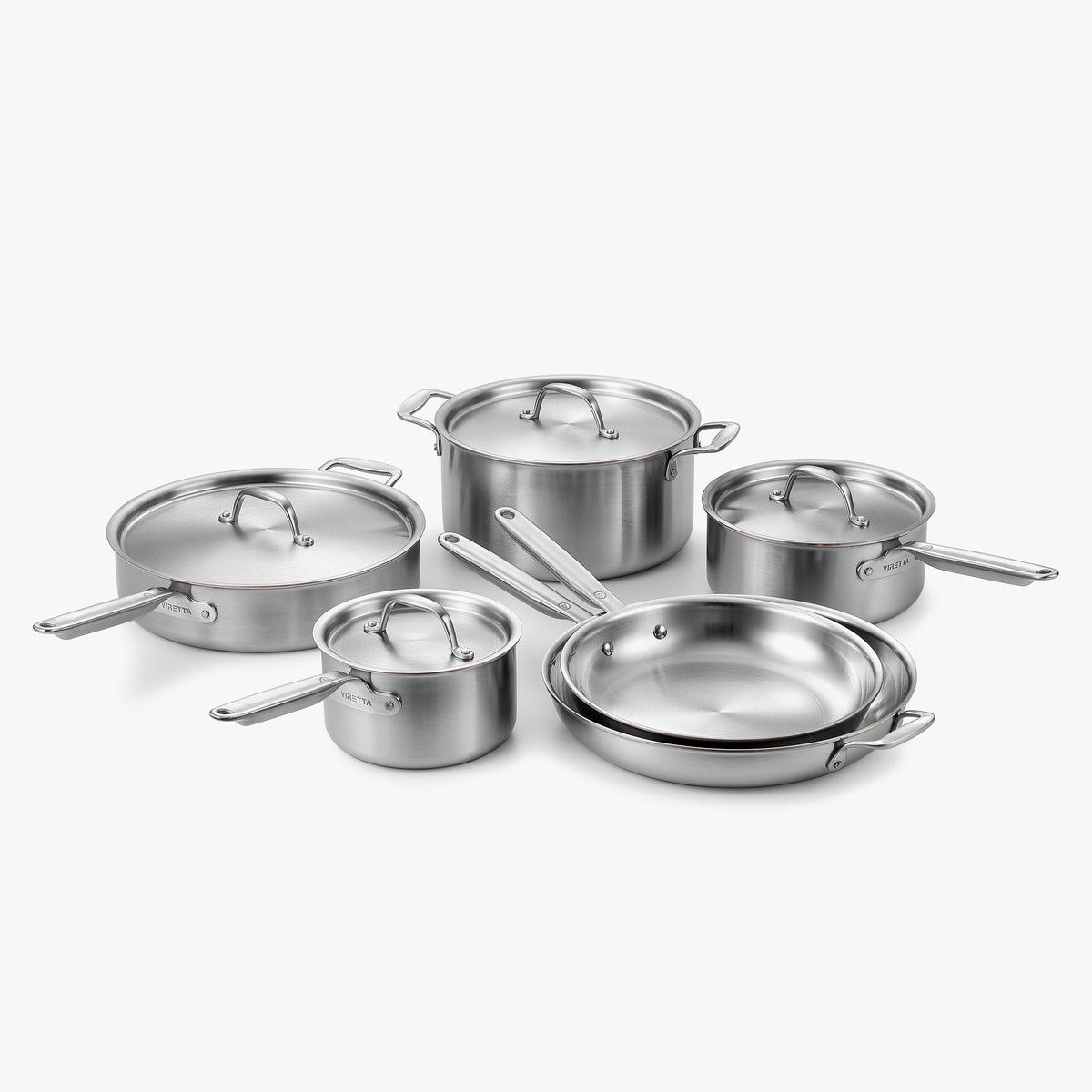 Kockset i 5-Ply rostfritt stål med kopparkärna: kastruller Ø16 och Ø20 cm, gryta Ø24 cm, sautépanna Ø28 cm och stekpannor Ø26 och Ø30 cm, med lock i rostfritt stål, sett snett framifrån
