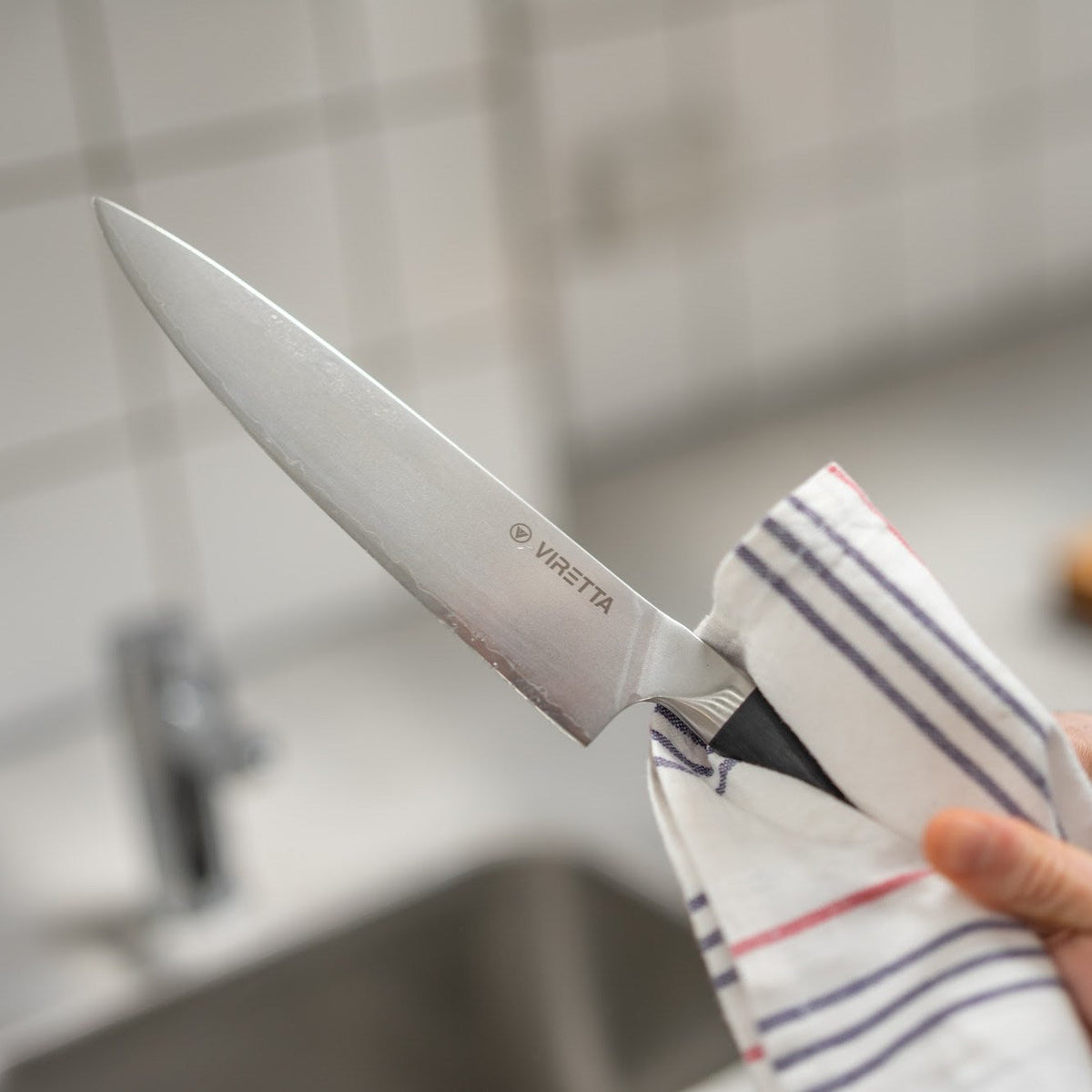 En Shōjin Aira kockkniv torkas med en kökshandduk vid diskhon
