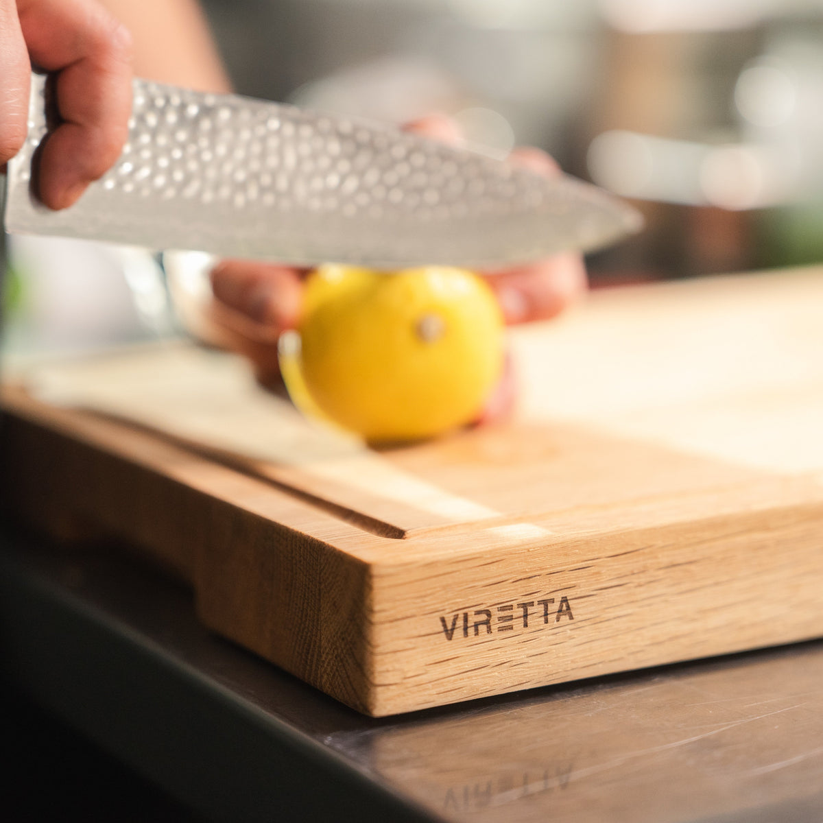 En citron skärs på en skärbräda i ek med saftränna och VIRETTA ingraverat i kanten