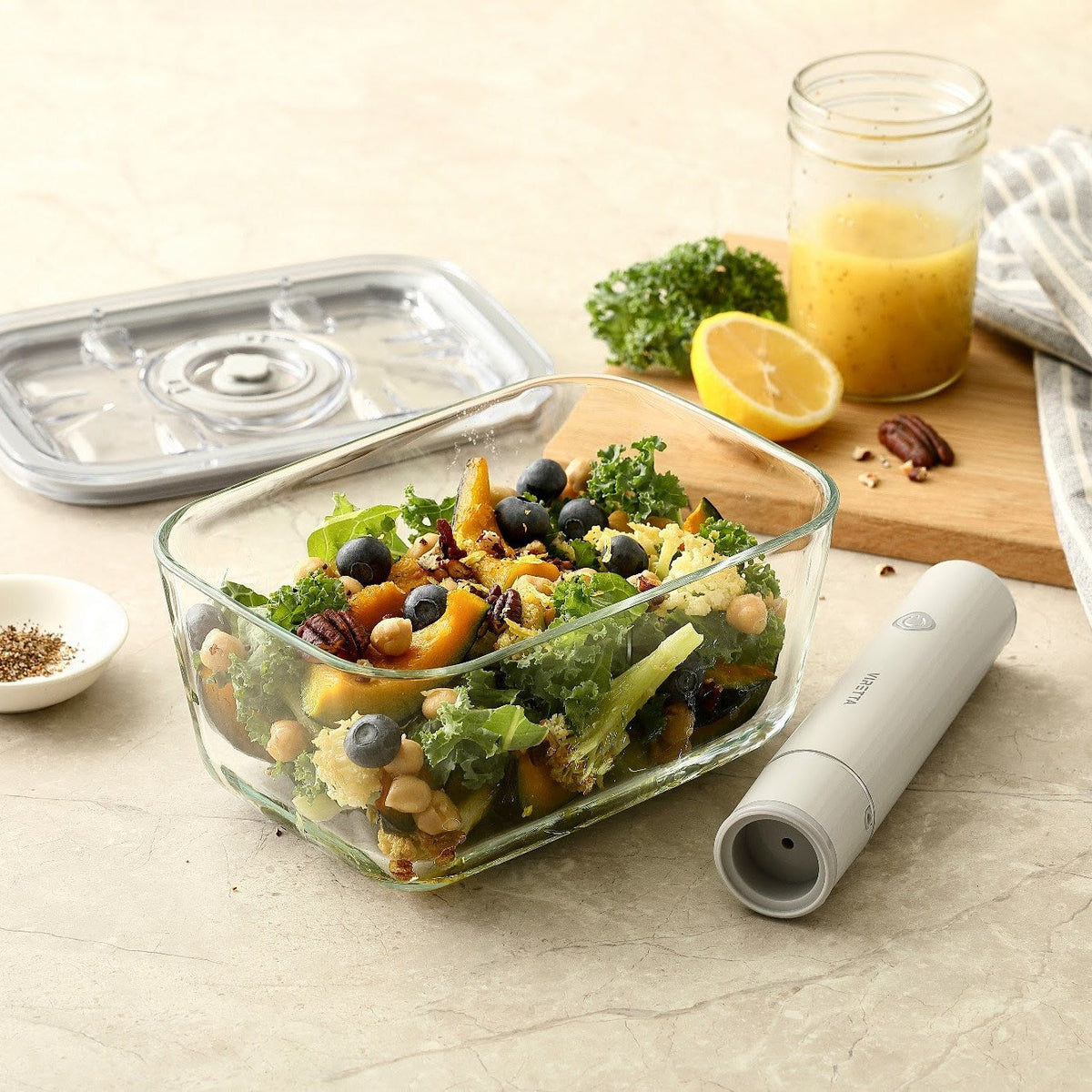 Vakuumbehållare i glas med sallad – locket och den elektriska vakuumpumpen ligger bredvid