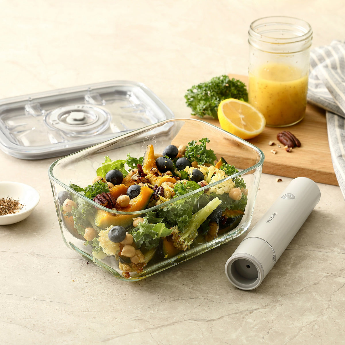 Vakuumbehållare i glas med sallad – locket och den elektriska vakuumpumpen ligger bredvid