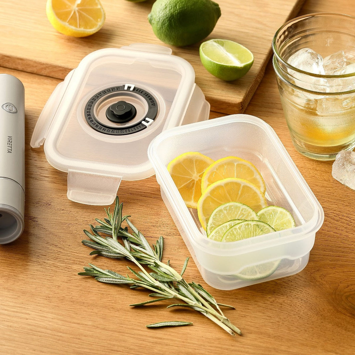 Vakuumbehållare i plast med citron- och limeskivor – locket och den elektriska vakuumpumpen ligger bredvid