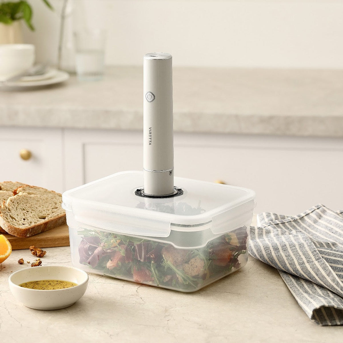 Den elektriska vakuumpumpen placerad på locket till en vakuumbehållare i plast med sallad