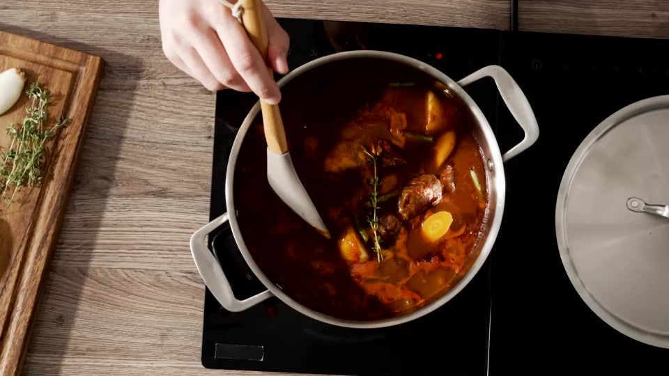 En gryträtt rörs om med en träslev i grytan på en induktionshäll